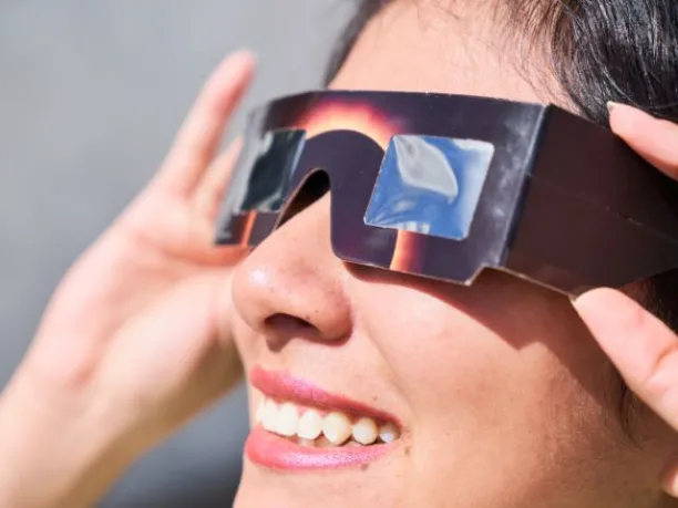 a woman wearing special solar eclipse viewing glasses