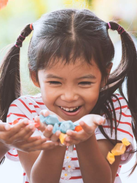 Young girl with smiling and looking a colored rocks
