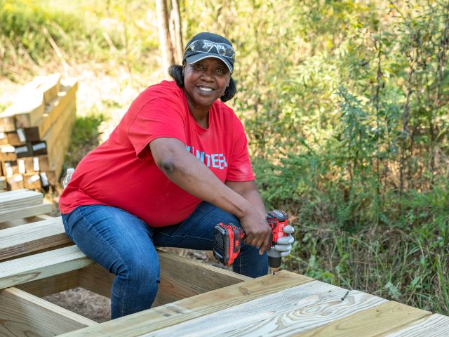 A woman drills a screw into a new boardwalk as part of an employee engagement activity on National Public Lands Day.