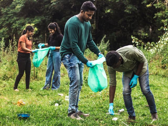 a group of young adults pick up trash near a local waterway