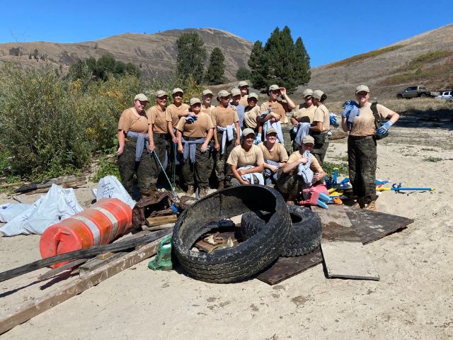 a group of NPLD volunteers pose for a photo with a pile of garbage collected during an event in Julietta ID