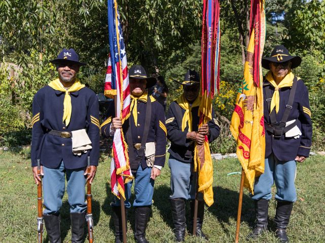 four men in buffalo soldier uniform hold flags as they pose during National Public Lands