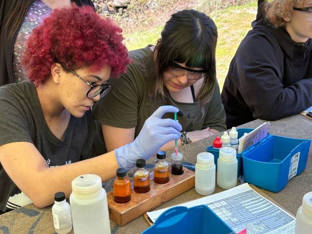 a high school student tests local river water during an environmental education STEM program