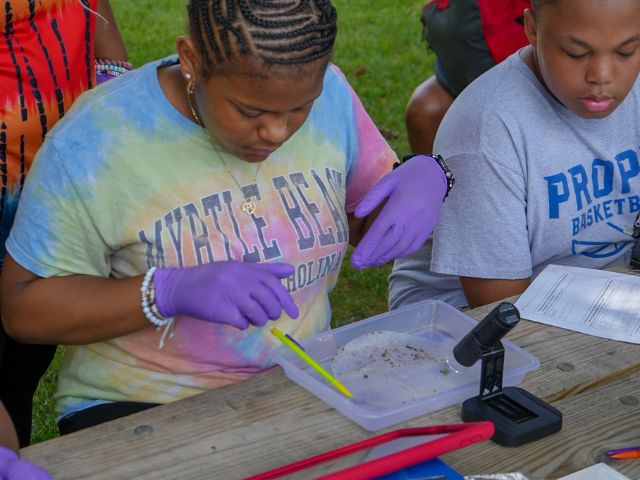 a student analyzes a water sample from a local source as part of an environmental education program. 