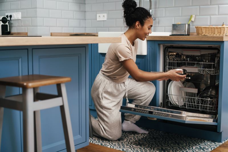 Woman using dishwasher to save water in the kitchen