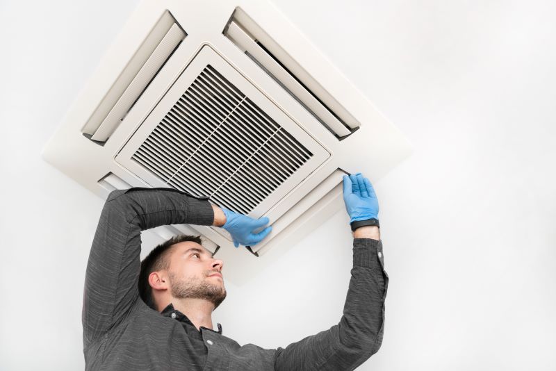 man replacing air conditioning filter in ceiling vent to save on energy cost