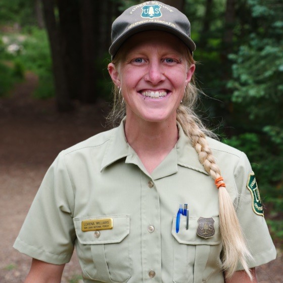 a photo of a blonde woman with a braided ponytail wearing a US Forest Service Ranger uniform