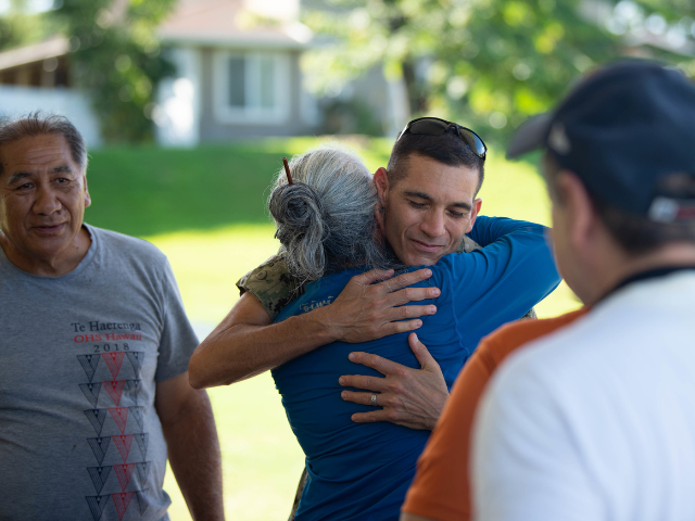 A member of the Navy hugs a local Native Hawaiian elder during a ceremony at the fishpond.