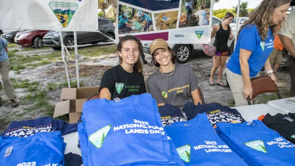 Smiling young people behind a table of shirts