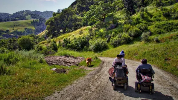 two women in all terrain electric wheelchairs on a trail in the San Francisco Bay area
