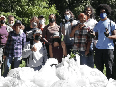 photo of group standing in front of pile of trash bags after a clean-up.