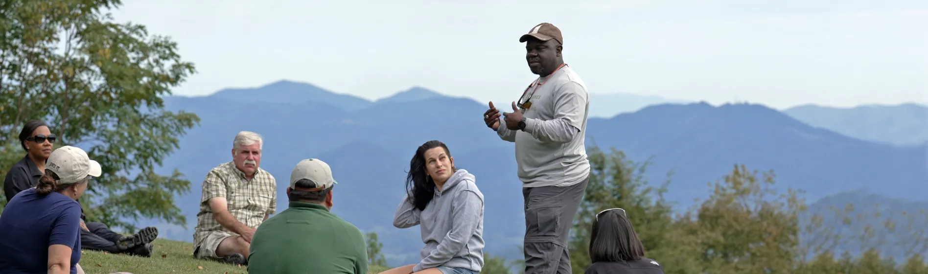 Man speaking to group in mountain outdoor setting