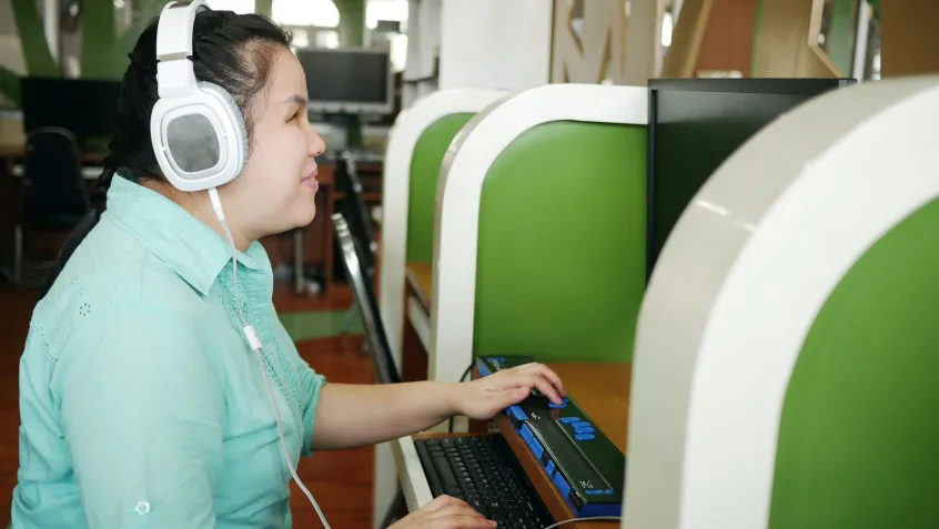 A woman with visual impairments uses a special keyboard while on the computer