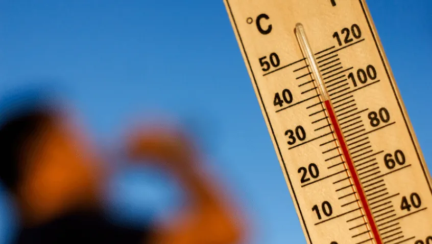 thermometer reading 100 degree F with a blurred photo of person drinking water 