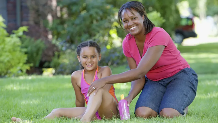 Mother applying sunblock to her daughter in the garden