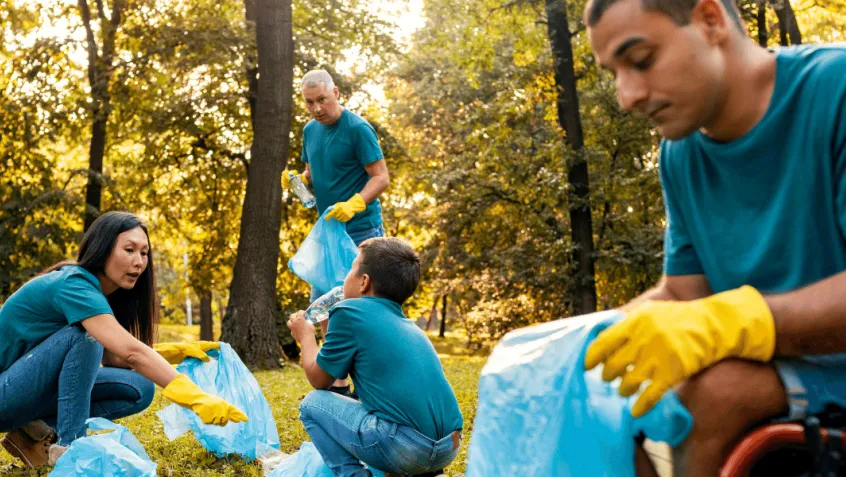 group of diverse people, one in a wheelchair, collecting litter in a forested area