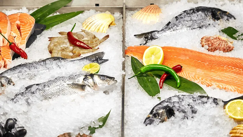 Photo of various seafoods on ice in a supermarket fridge
