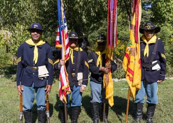 four men in buffalo soldier uniform hold flags as they pose during National Public Lands