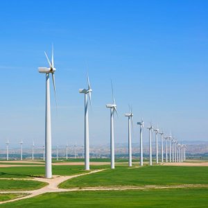 wind turbines lined up along a long open space and mountains in the background