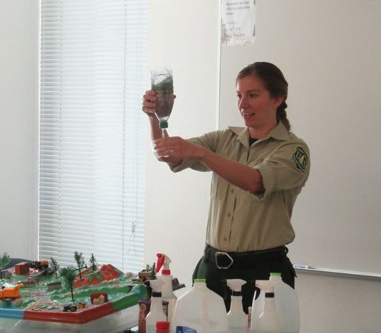 a forest service employee instructs students on water quality