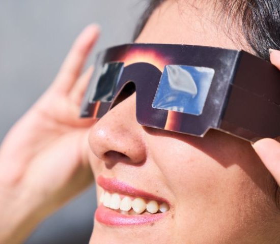 a woman wearing special solar eclipse viewing glasses