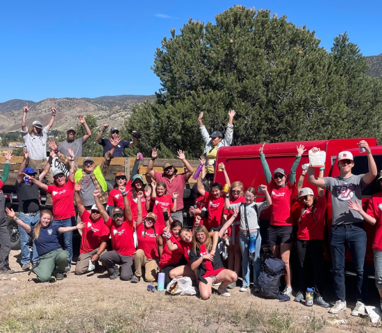 People in a group smiling, with their arms in the air after an NPLD clean up