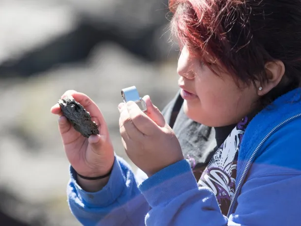 Photo of student looking at rock with magnifying glass