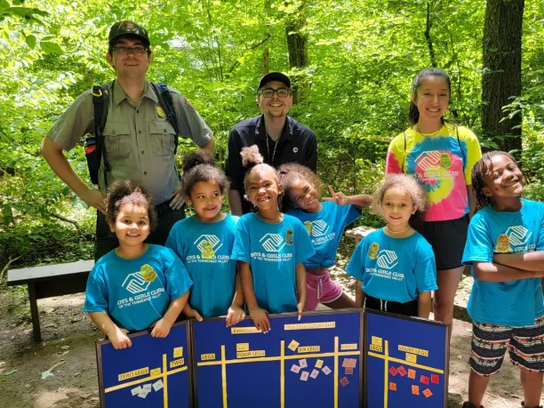 Photo of young students from Boys & Girls Club smiling and standing with National Park Ranger and AmeriCorps Volunteer