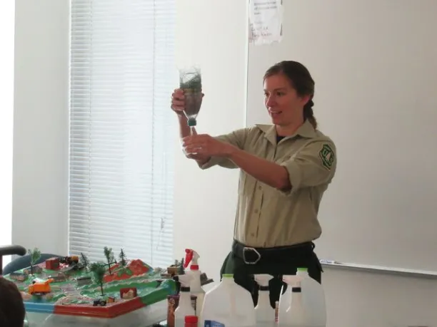 a forest service employee instructs students on water quality