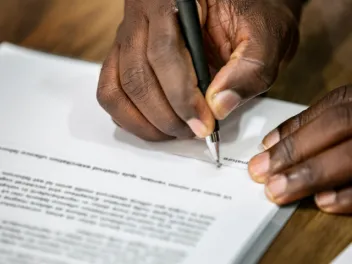 hand with pen signing document
