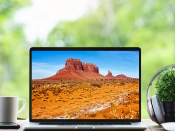 a laptop computer sits on a table with an image of southwestern mountains on a screen for national public lands day virtual event