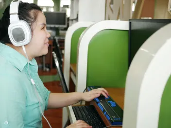 A woman with visual impairments uses a special keyboard while on the computer