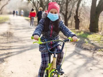 Girl with a mask on riding a bike